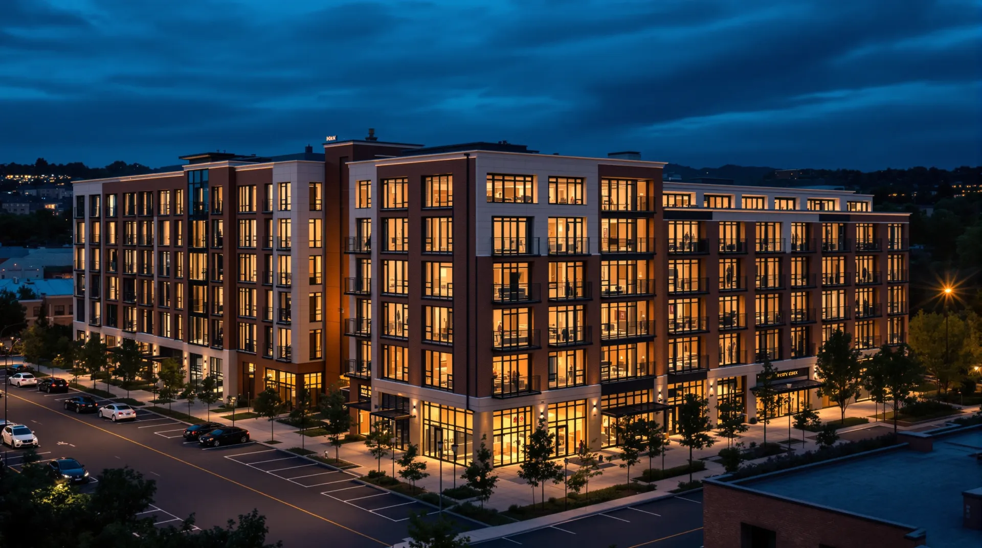 Mid-rise apartment building at dusk with lit units and street-level parking.